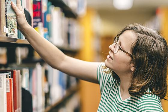 图为足球外围买球靠谱的一名女学生从图书馆书架上取下一本书